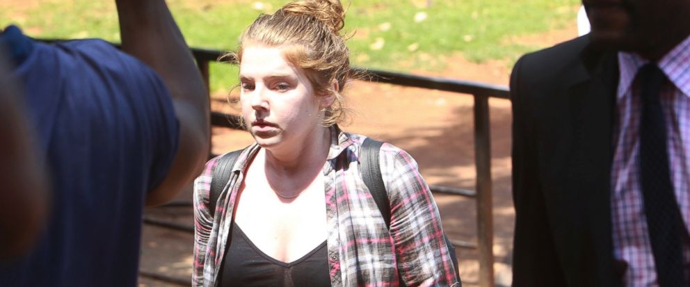 U.S. Citizen Martha O Donovan appears at the Harare Magistrates court escorted by a plain clothes police officer shielding her face in Harare, Saturday, November, 4, 2017. Police arrested and charged Donavan with subversion for allegedly insulting P