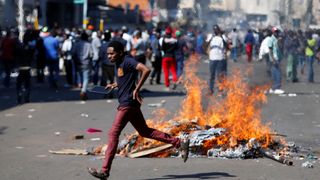 A man runs as supporters of the opposition Movement for Democratic Change party (MDC) of Nelson Chamisa burn barricades in Harare, Zimbabwe