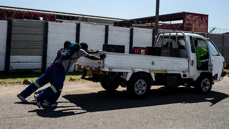 Men push their truck outside Delta Beverages in Bulawayo, opting to wait overnight in a queue although their car had run out of diesel [Tendai Marima/Al Jazeera]