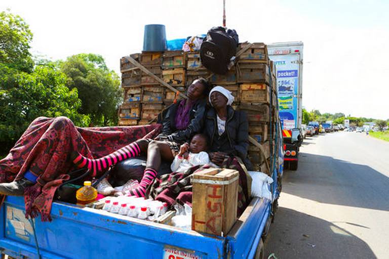 In this photo taken on Friday Dec, 21, 2018, a family sleeps in the back of a truck while waiting in a fuel queue in Harare. The Christmas lights are up in Zimbabwe's capital but the mood is less than festive as the country grapples with an economic crisis that prevents many families from enjoying the holiday season. Zimbabwe is experiencing its worst economic meltdown in a decade.