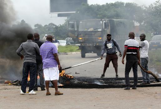 Plain clothed soldiers remove the barricade as protesters gather during a demonstration over the hike in fuel prices in Harare, Zimbabwe, Tuesday, Jan. 15, 2019. (AP Photo/Tsvangirayi Mukwazhi)