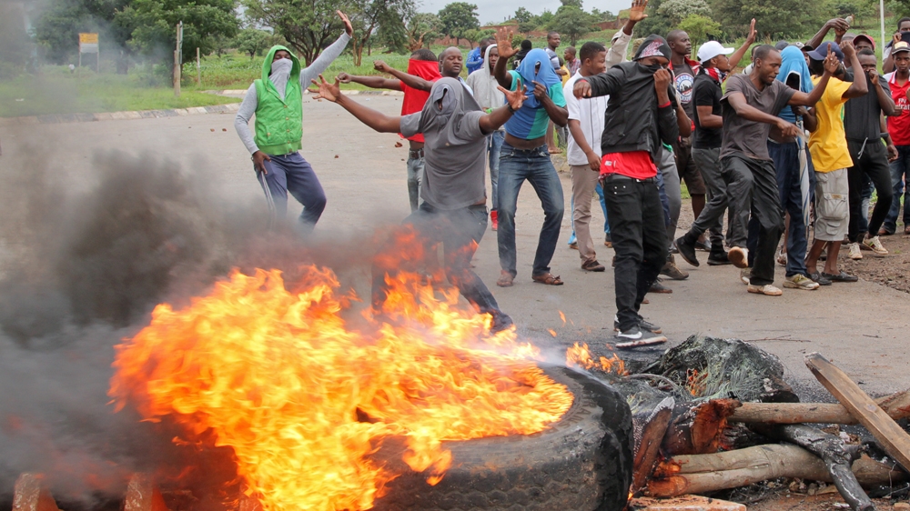 DATE IMPORTED:15 January, 2019Protesters stand behind a burning barricade during protests on a road leading to Harare, Zimbabwe, January 15, 2019. REUTERS/Philimon Bulawayo Zimbabwe protest