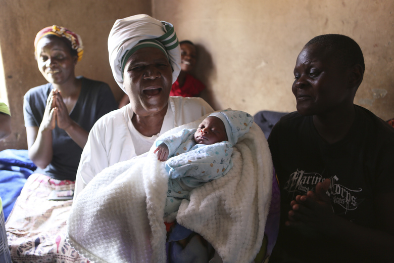 Esther Zinyoro Gwena holds one of the babies she has just delivered in her tiny apartment in the poor suburb of Mbare in Harare, Zimbabwe, Saturday, Nov. 16, 2019. Grandmother Esther Zinyoro Gwena claims to be guided by the holy spirit and has become a local hero, as the country’s economic crisis forces closure of medical facilities, and mothers-to-be seek out untrained birth attendants.(AP Photo/Tsvangirayi Mukwazhi)