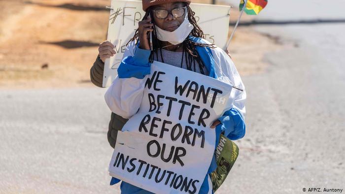 Tsitsi Dangarembga holding a placard that reads: We want better, reform our institutions. Tsitsi Dangarembga holding a placard that reads: We want better, reform our institutions.