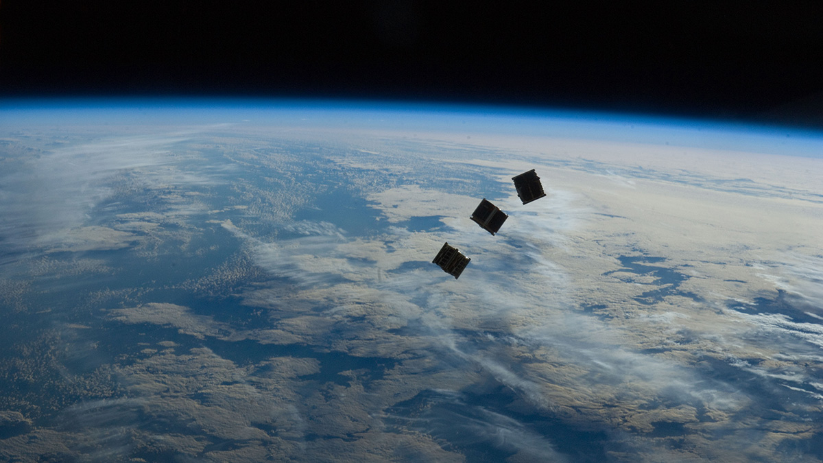 Three CubeSats float above Earth.