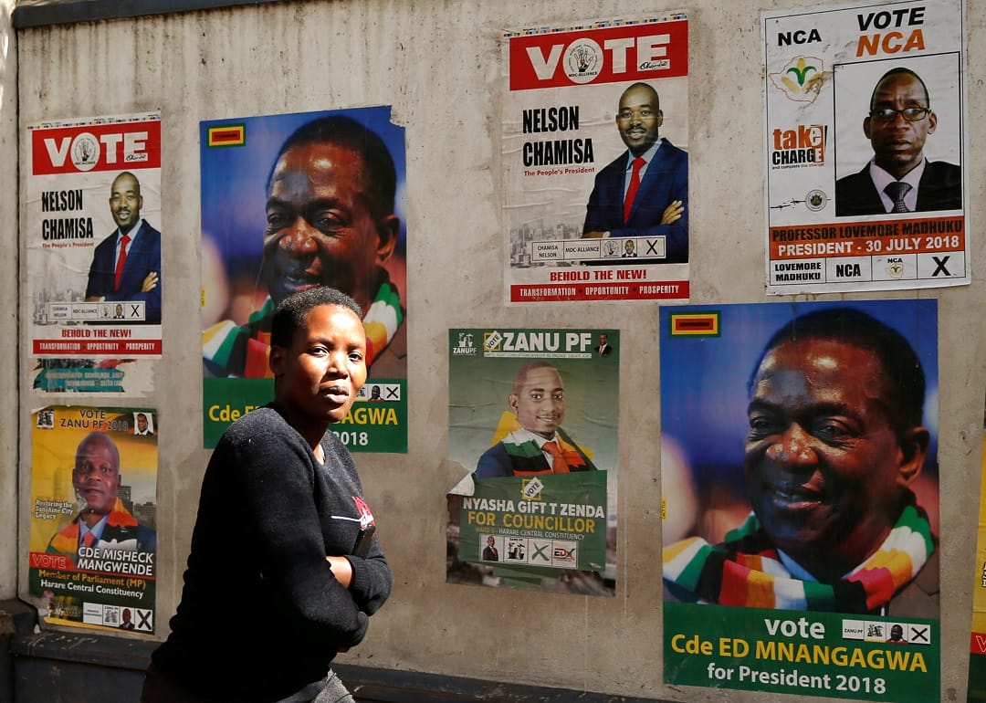 A woman walks past election posters in Harare