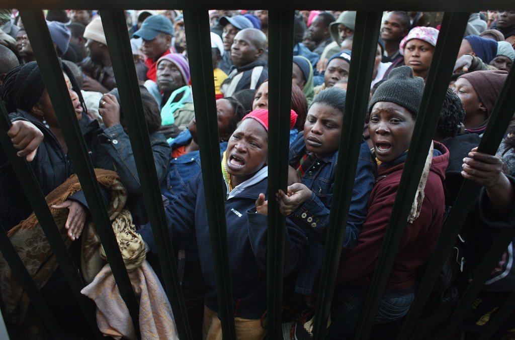 Illegal Immigrants, most of them from Zimbabwe, are smashed against a fence at the entrance of a refugee centre June 17, 2008, in Johannesburg, South Africa. In 2008, with the economic collapse of Zimbabwe and widespread political oppression, more than 3 million Zimbabweans flooded across the border into South Africa. (Photo by John Moore/Getty Images)