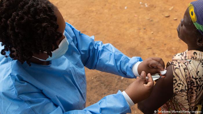 A woman gets vaccinated with an infant on her back A woman gets vaccinated with an infant on her back