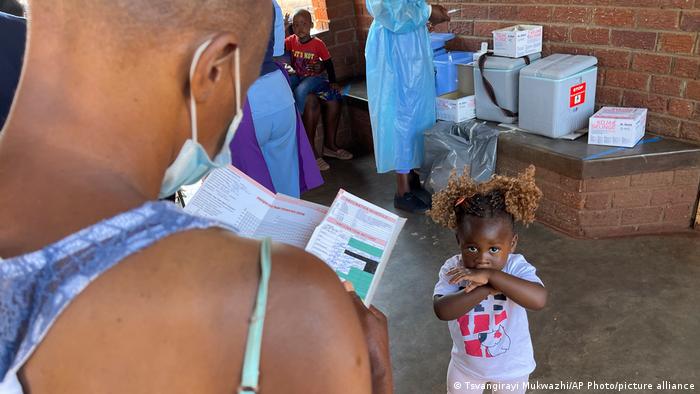 A parent waits for her child to receive a measles vaccination jab at a local clinic in Harare