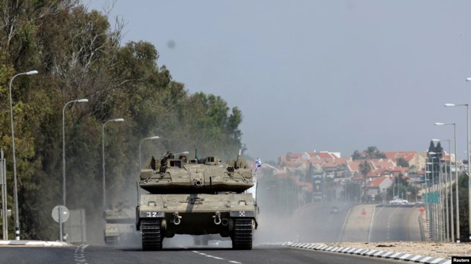 Israeli tanks drive on a road near Sderot in southern Israel, following a mass infiltration by Hamas gunmen from the Gaza Strip, Oct. 8, 2023. 