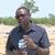 DW Freelance Privilege Musvanhiri reporting as an elephant walks in the background.