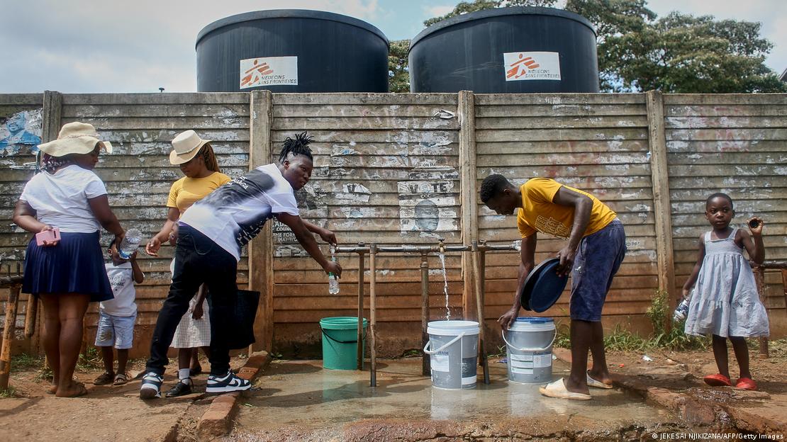 Several young people are filling up bottles and buckets with safe drinking water